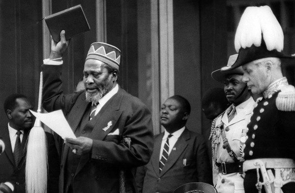 Jomo Kenyatta takes the oath during his swearing-in as Kenya's first Prime Minister on June 1, 1963. On his right is Governor Malcolm Macdonald.