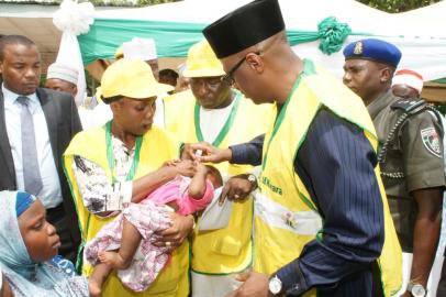 Kwara State Governor - Dr Abdulfatah Ahmed (right), administering polio vaccine on a child while the 