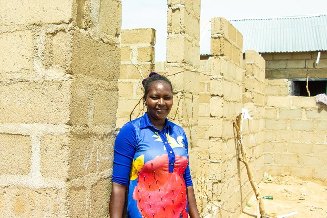 Faraa stands in front of the house she has started building with proceeds from her pasta business, a few meters away from the host community that welcomed her in Yola